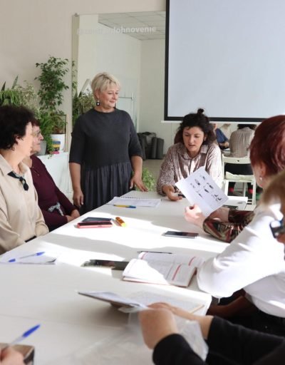 Заняткі ў «Акадэміі 50+». У цэнтры за сталом – выкладчыца Сабіна Курбанава, побач з ёй стаіць Святлана Красная. Фота: 1387.io